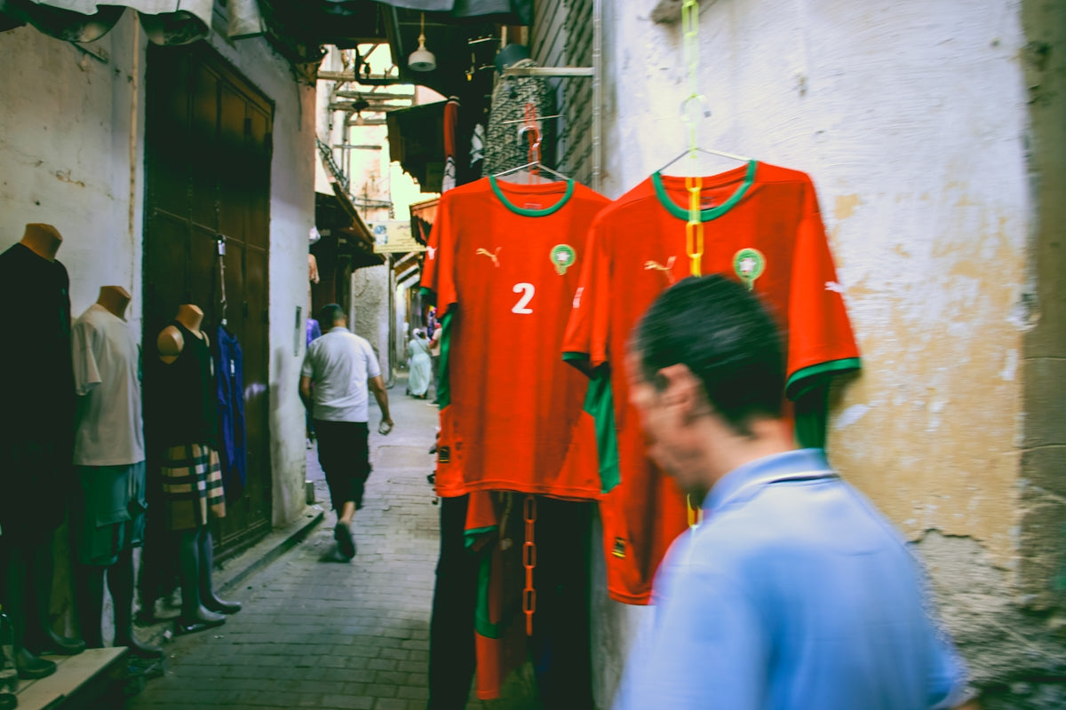 Moroccan soccer jerseys hanging in a narrow alley.