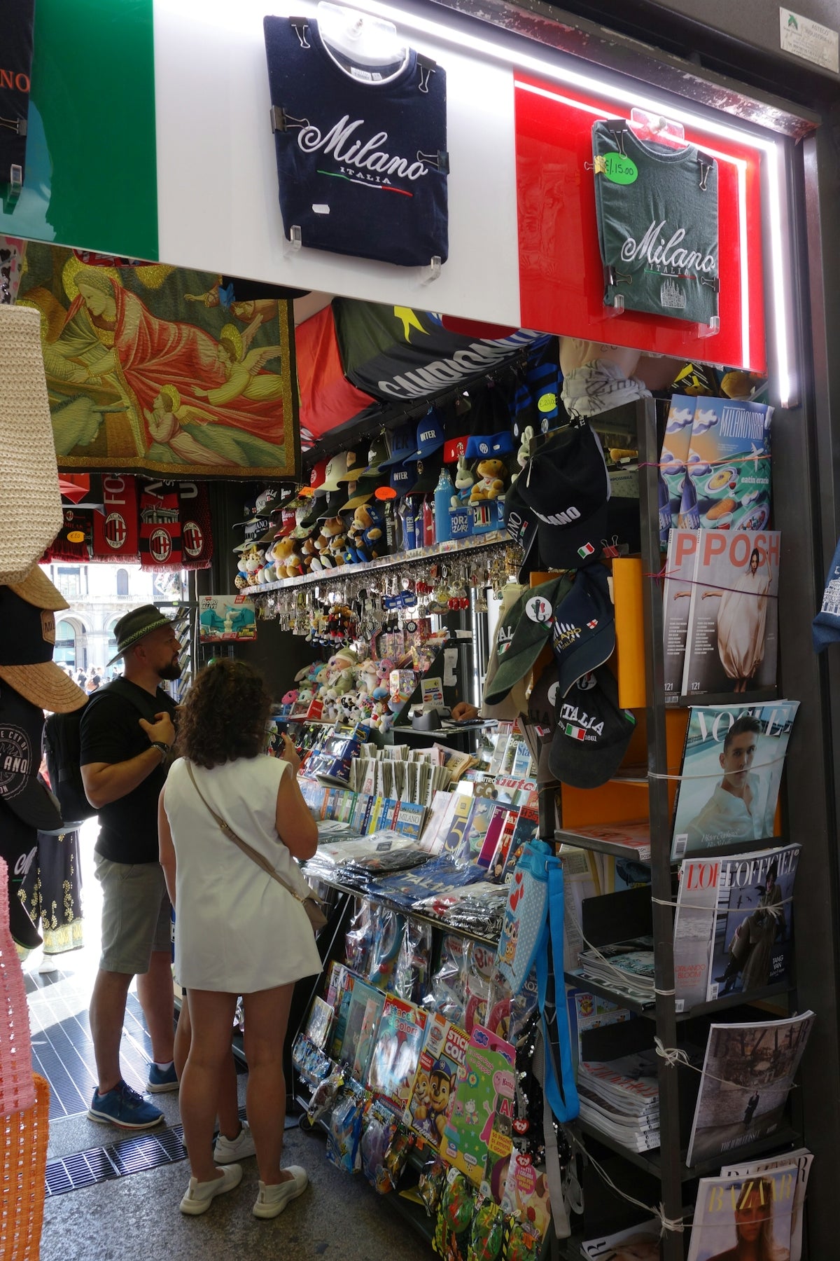 People browse a souvenir kiosk with italian flags and merchandise.